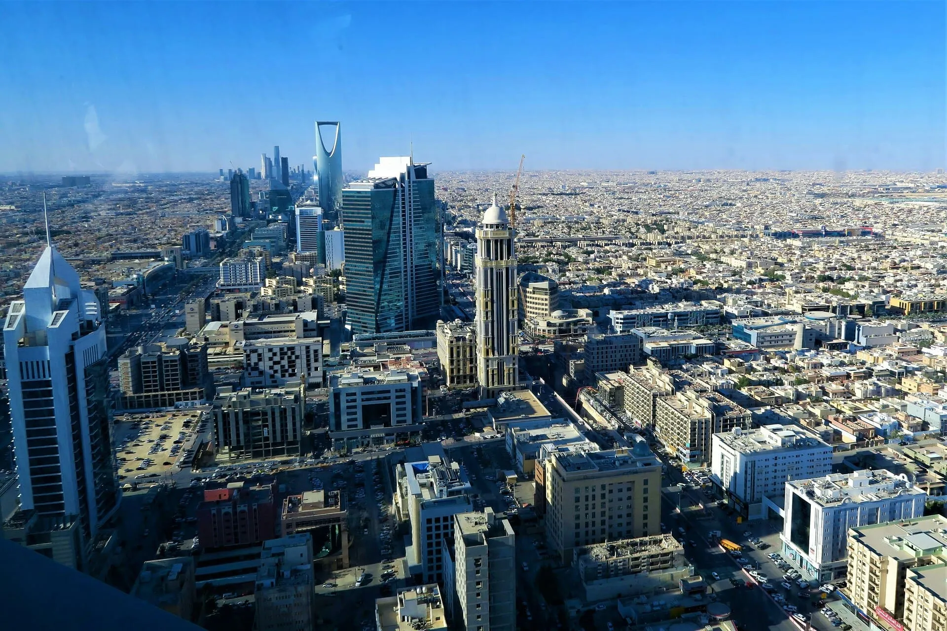 Riyadh from high above, the Kingdom Centre rising over the city under a clear sky.